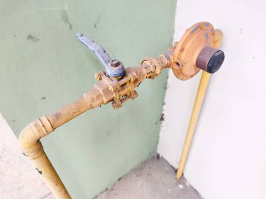 Ev ve endüstriyel tesisatta kullanılan eski su vanası ve sarı boyalı metal borular.