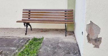 Hasarlı duvarın yanındaki eski ahşap bankta