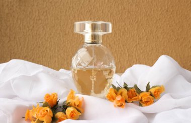 Female perfume centralized on white fabric with orange color flowers clipart