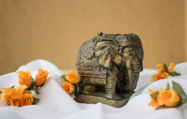 Antik Hint fili beyaz kumaş ve turuncu çiçeklerin üzerindeki küçük heykel