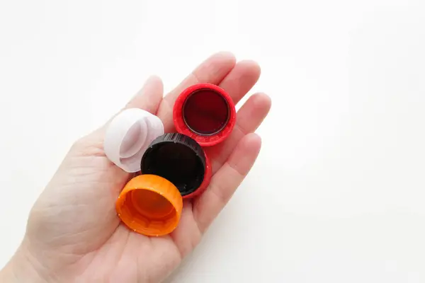 Plastik şişe kapaklarını tutan insan eli