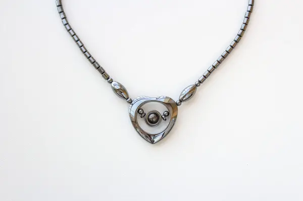 Beyaz arka planda izole edilmiş siyah rodyum kaplama kalp şeklinde kadın kolyesi. Parlak metal moda tasması.