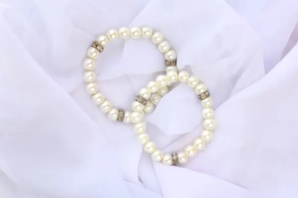 Gelin için iki fildişi sahte bilezik. Beyaz peçeli kumaşın üstündeki kadın takıları..