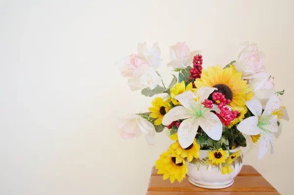 stock image Horizontal still life studio shot of a vase with yellow and white plastic scenic flowers. Springtime sunflower arrangement background with copy space.