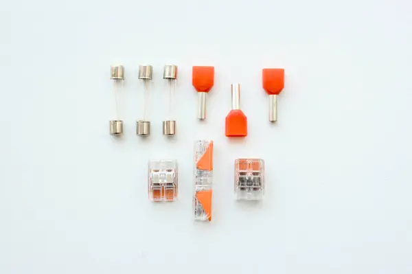 Elektrik kablosu ve kablo bileşenleri, sigortalar, terminaller gibi aksesuarlar, beyaz arka planda izole edilmiş kablo bağlantıları. Düzenli elektrikçi çalışma masası, endüstriyel işler için parçalar..