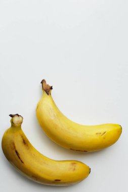 İki muz dikey beyaz arkaplanda ve kopyalama alanı var. Sağlıklı, organik, vejetaryen diyet yemekleri için vitamin zengini. Tatlı ve besleyici tropikal meyveler.