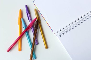 Boş bir not defterinin yanında renkli tükenmez kalemler var. Okul, sanat sınıfı ve çizim dersi için yaratıcılık kavramı.