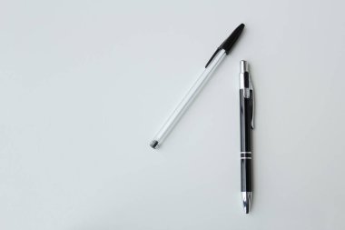 Beyaz arka planda izole edilmiş iki siyah beyaz tükenmez kalem. Ofis malzemeleri, okul kırtasiyesi, yazarlık etkinliği konsepti. Boşluğu kopyala.