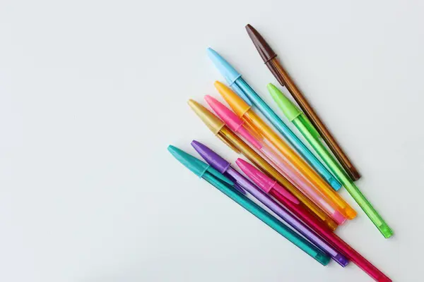 Beyaz arkaplanda köşegen şeklinde dizilmiş renkli kalemler. Renk kırtasiyesi, okul malzemeleri, sanat dersi, yaratıcılık kavramı.
