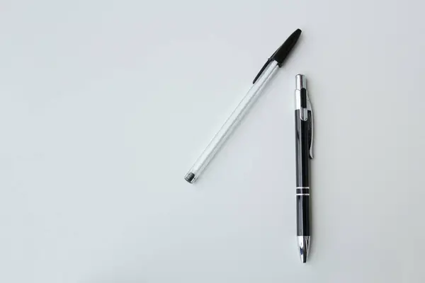 Beyaz arka planda izole edilmiş iki siyah beyaz tükenmez kalem. Ofis malzemeleri, okul kırtasiyesi, yazarlık etkinliği konsepti. Boşluğu kopyala.