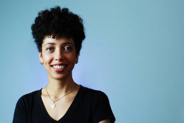 Short hair black Brazilian woman smiling, wearing black t-shirt and silver necklace, against a blue background with copy space. Horizontal banner, cheerful afro-descendant lady, female portrait. clipart