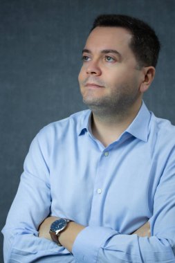 Kollarını kavuşturup yukarı bakan düşünceli bir iş adamı. Şirket işi, kariyer planlaması, ofis işi, yönetici ya da CEO rolü için mükemmel. Mavi arkaplanda kopya alanı olan stüdyo portresi.