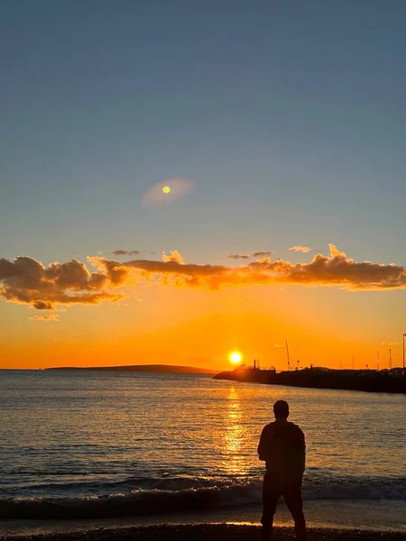 海岸の男は夕日が楽しい瞬間を隠す海に向かっている — ストック写真