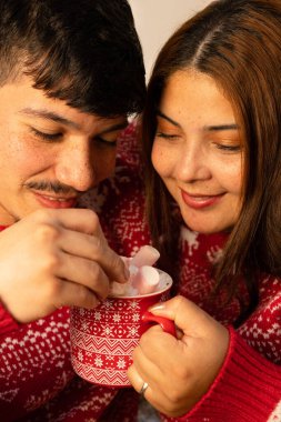 Noel arifesinde eşofmanlı neşeli çift kremalı ve şekerli çikolata hazırlıyor.