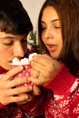 Genç bir çift Noel arifesinde noel şekerlemeleri ile sıcak çikolata yiyor.
