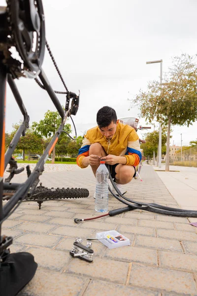 young sportsman crouching on the ground repairing his bicycle