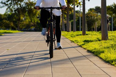 Genç kız sabahın köründe bisiklet sürerek güzel parkta yürüyüşe çıkar.