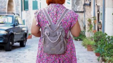 Çiçekli, kızıl saçlı genç bir kadın Mallorca İspanya 'nın Valldemossa kasabasında yürüyor.