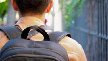 Siyah çantalı ve kahverengi gömlekli genç adam güneşli bir günde Valldemossa Mallorca İspanya sokaklarında yürüyor.