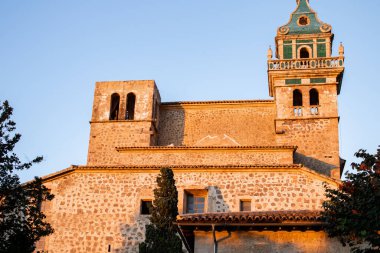 Valldemossa 'daki eski bir yapı, sıcak güneşin üzerinde parladığı, ağaçlarla çevrili ve muhteşem bir gökyüzü olan.
