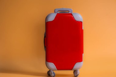 Kırmızı minyatür bavul turuncu mercan arka planda izole edilmiş seyahat ve turizm konsepti