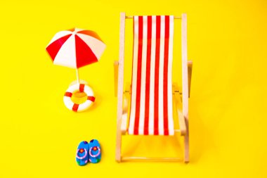 Kırmızı hamak, parmak arası terlik, şemsiye ve yanında süzülen sarı arka plan.