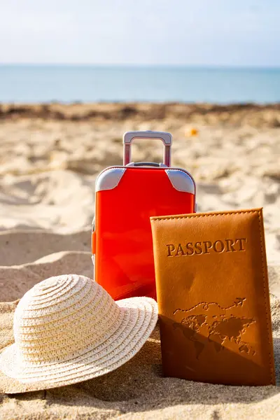 Güneşli bir günde kumsalda bavul ve pasaport, seyahat ve turizm kavramı.