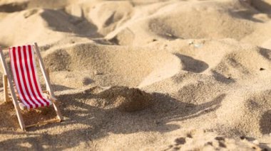 Bir şemsiyenin yanında iki küçük kırmızı ve mavi hamak. Güneşli bir günde kumsal, yatay ağır çekim, yaz tatili konsepti