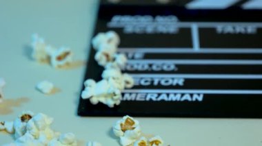 Beyaz çizgili siyah ahşap bir alabora üzerinde patlamış mısır, sinema kavramı.