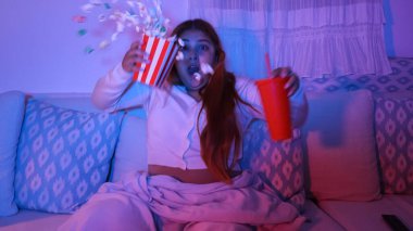 Korkmuş kadın, geceleri koltukta oturmuş korku filmi izlerken karton kovadan patlamış mısır düşürüyor.