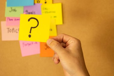 Erkek el, soru işareti, sorgulama ve şüphe içeren bir kağıt tutuyor.