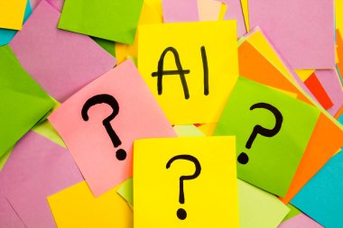 Üzerinde siyah harf olan sarı yapışkan kağıt üzerinde yapay zeka, üzerinde soru işaretleri olan renkli kağıtlar, yapay zeka ve gelecekle ilgili soru kavramı.