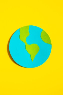 Sarı izole edilmiş arka plandaki kağıt gezegen Dünya 'nın dikey görüntüsü.
