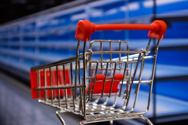 Shopping cart in a supermarket with empty shelves in the background out of focus. Concept of food shortage and lack clipart