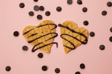 Heart shaped cookies with melted chocolate and sprinkles scattered on a pink background. Valentine's Day concept clipart