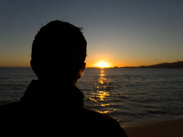 İnsanoğlunun siluetine yakın kışın gün batımını seyrederken ufukta güneş batarken