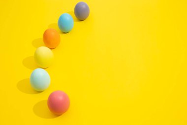 Çeşitli renklerde paskalya yumurtaları, kopya alanı olan sarı bir zemin üzerine dizilmiş. Paskalya dekorasyonu