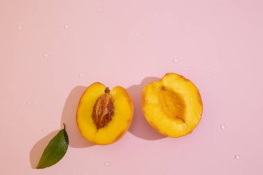 Fotokopi alanı olan pembe arkaplanlı şeftalinin üst görüntüsü. Kadife tenli portakal meyvesi ve sulu, tatlı ve aromatik posa.