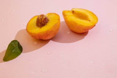 Fotokopi alanı olan pembe arkaplanlı şeftalinin yarısını kapat. Kadife tenli portakal meyvesi ve sulu, tatlı ve aromatik posa.