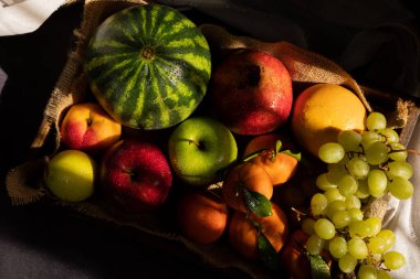 Kırsal bir ahşap tepside taze toplanmış meyvelerin üst görüntüsü. Sabah güneşinin pencereden içeri girmesiyle koyu arkaplan aydınlanıyor. Kara meyve yemeği.