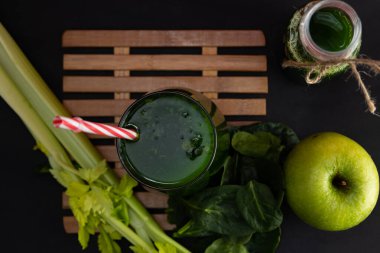 Ispanak, kereviz ve yeşil elma suyu, siyah arka planda, kırmızı bir cam bardakta. Doğal ve sağlıklı bir içecek.