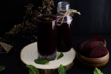Koyu arka planda tahta bir kütük üzerinde pancar püresi, yüksek antioksidanlı koyu kırmızı sağlıklı bir içecek. Koyu yiyecek