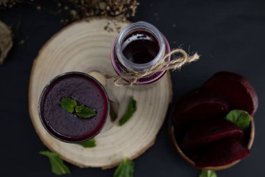 Koyu bir arka planda tahta bir kütük üzerinde pancar smoothie 'nin üst görüntüsü, yüksek antioksidanlı koyu kırmızı sağlıklı bir içecek. Kara yemek.