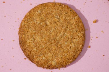 Pastel pembe zemin üzerinde tam buğdaylı yulaflı kurabiyeye aşırı yakın, buğday unuyla yulaf gevreğiyle karıştırılmış kurabiye, pişirmede geleneksel.