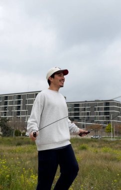 Bulutlu bir kış gününde ip atlayan genç bir adamın dikey görüntüsü. Açık hava sporu