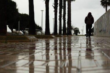 Yağmurlu bir günde ıslak bir sokakta yürüyen bir kadın, açık hava yaşam tarzı.