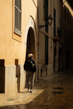 Güneşli bir günde, Palma de Mallorca 'nın merkezinde yalnız bir sokakta yürüyen bir adam.