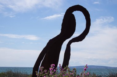 Güneşli bir günde arka planda mavi gökyüzü olan büyük soyut bir figür.