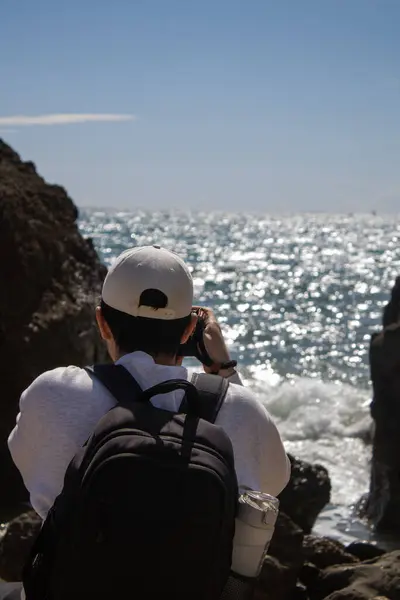 Güneşli bir günde Akdeniz 'i fotoğraflayan kayaların arasındaki insanın dikey görüntüsü