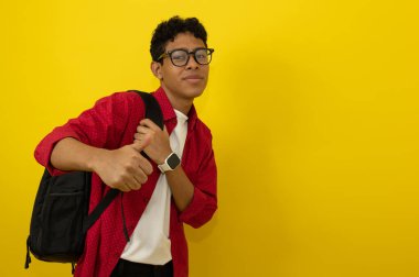 Genç kahverengi tenli Latin, üniversite öğrencisi kırmızı günlük kıyafetler giyiyor ve sarı arka planda fotokopi alanı var.